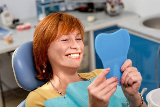 Woman admiring her new smile in a mirror
