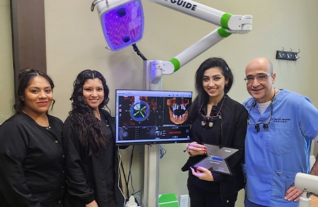Irving dentist and team members standing next to monitor showing digital models of jawbone
