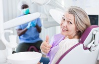 Senior woman giving a thumbs up in dental chair