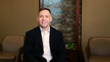 Man in black suit jacket giving interview in dental office