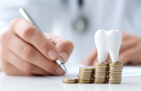 Tooth model sitting on top of stack of coins