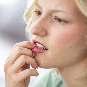 Concerned woman biting her fingernail