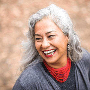 Senior woman with grey shirt smiling outside