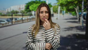 Concerned woman in striped shirt touching her lip