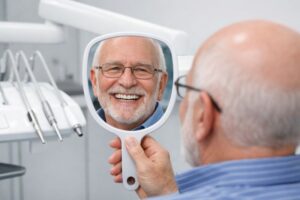Happy senior dental patient smiling in mirror